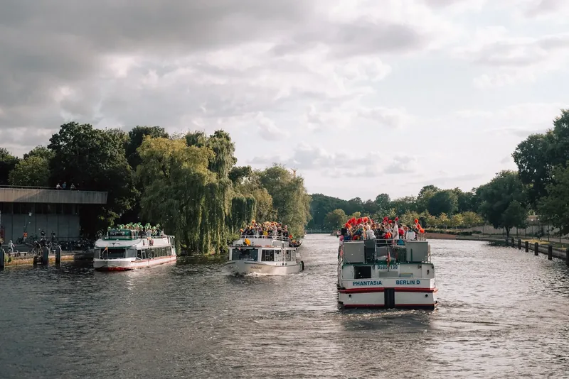 Mehrere Fahrgastschiffe auf der Spree zwischen grünen Ufern